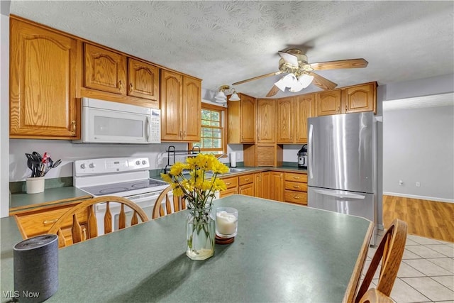 378 Stahl Ave, Cortland, OH 44410 - kitchen featuring white appliances, a ceiling fan, light tile patterned floors, brown cabinets, and a textured ceiling