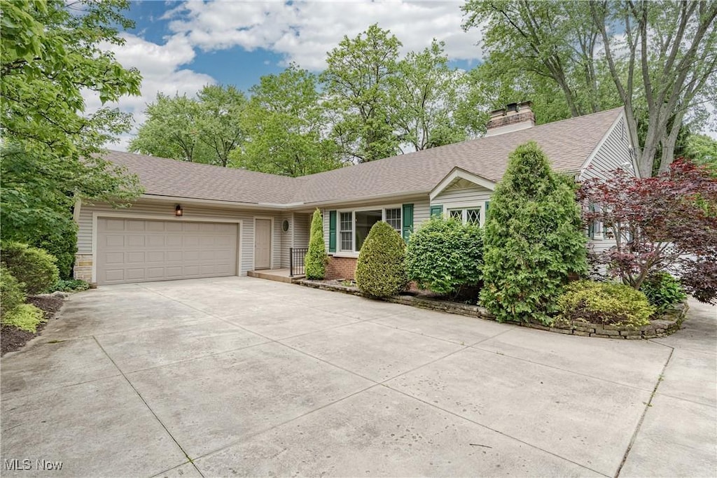 2443 Ridgewood Rd, Akron, OH 44313 - single story home with concrete driveway, an attached garage, a chimney, and a shingled roof