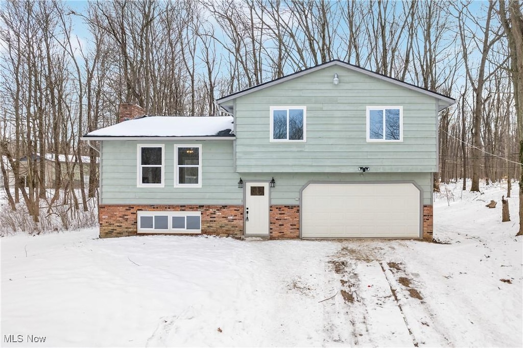 4450 John Thomas Rd, Ravenna, OH 44266 - view of snow covered exterior with a garage, brick siding, and a chimney