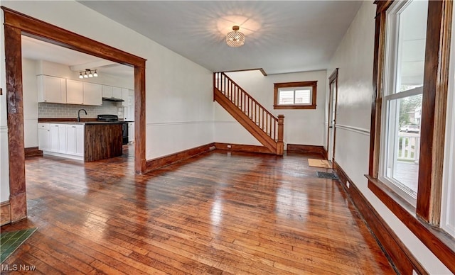 802 N Main St, Uhrichsville, OH 44683 - unfurnished living room with dark wood-type flooring, stairs, and baseboards