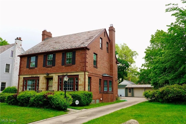 2323 Miramar Blvd, University Heights, OH 44118 - view of front of property with brick siding, a front yard, stone siding, an outdoor structure, and a garage