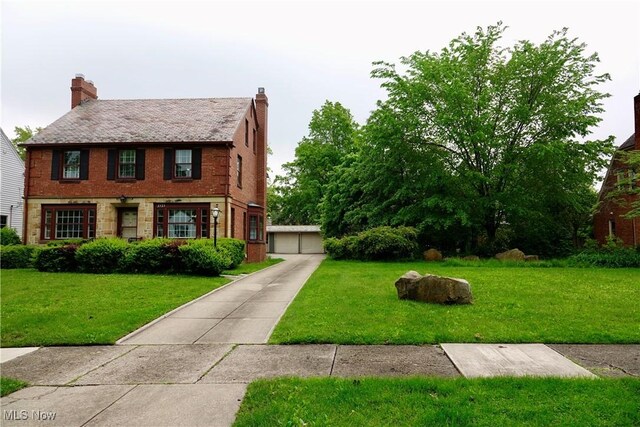 2323 Miramar Blvd, University Heights, OH 44118 - view of front facade with brick siding, a front yard, a chimney, and a garage