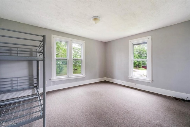 492 W Pershing St, Salem, OH 44460 - unfurnished bedroom with carpet flooring, multiple windows, baseboards, and a textured ceiling