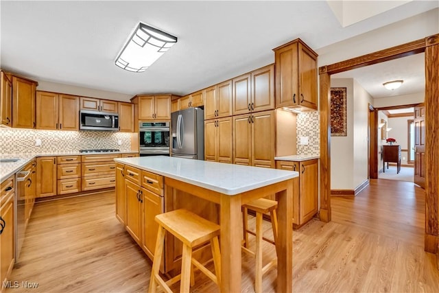 1271 Emerald Creek Dr, Broadview Heights, OH 44147 - kitchen featuring stainless steel appliances, light countertops, decorative backsplash, light wood finished floors, and a center island