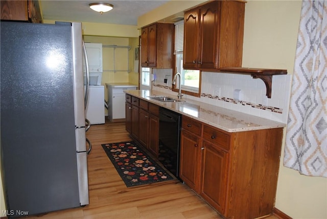 13350 Baumhart Rd, Amherst, OH 44001 - kitchen with freestanding refrigerator, dishwasher, a sink, estacked washer and dryer, and light wood-type flooring
