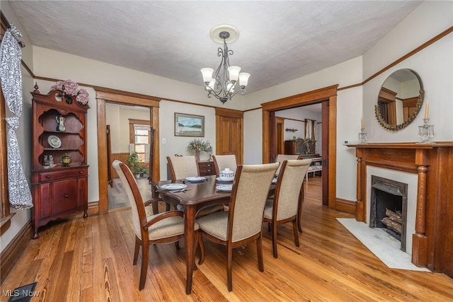 201 E Spring St, Marietta, OH 45750 - dining room featuring a chandelier, light wood-style flooring, a high end fireplace, and baseboards