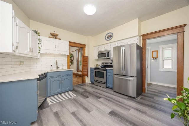 201 E Spring St, Marietta, OH 45750 - kitchen featuring stainless steel appliances, a sink, white cabinetry, wood finished floors, and a textured ceiling