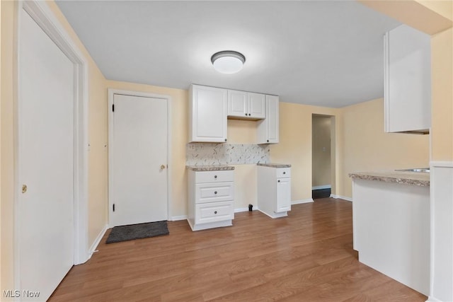 6525 Wales Ave NW, Massillon, OH 44646 - kitchen featuring light wood-style floors, white cabinetry, tasteful backsplash, light countertops, and baseboards