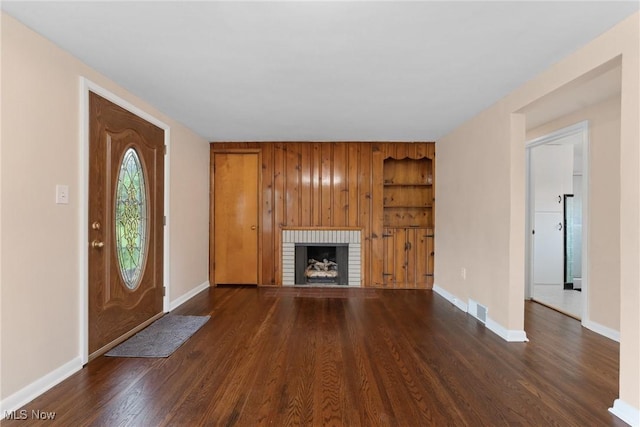 6525 Wales Ave NW, Massillon, OH 44646 - unfurnished living room with dark wood-style flooring, a brick fireplace, baseboards, and built in features