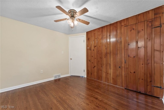 6525 Wales Ave NW, Massillon, OH 44646 - unfurnished bedroom with wood finished floors, baseboards, wood walls, and a ceiling fan