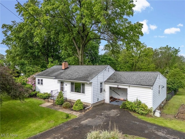 6525 Wales Ave NW, Massillon, OH 44646 - view of front of house featuring a chimney, a shingled roof, a front lawn, asphalt driveway, and an attached garage