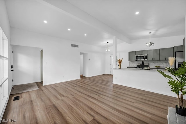 6482 Sherborn Rd, Parma Heights, OH 44130 - unfurnished living room featuring a chandelier, vaulted ceiling, light wood finished floors, recessed lighting, and baseboards