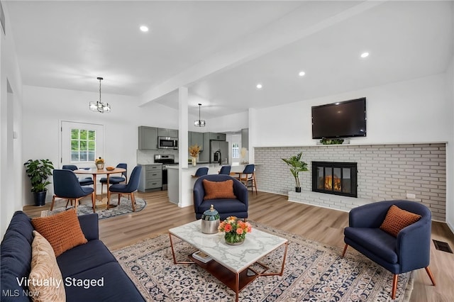 6482 Sherborn Rd, Parma Heights, OH 44130 - living area with light wood-style floors, a brick fireplace, a chandelier, and recessed lighting