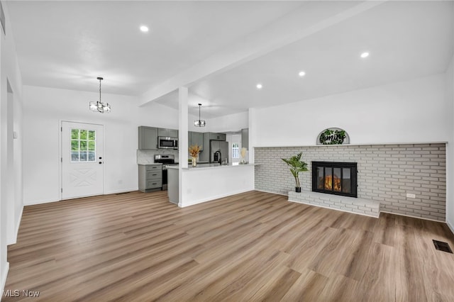 6482 Sherborn Rd, Parma Heights, OH 44130 - unfurnished living room featuring light wood-type flooring, a chandelier, a fireplace, recessed lighting, and baseboards