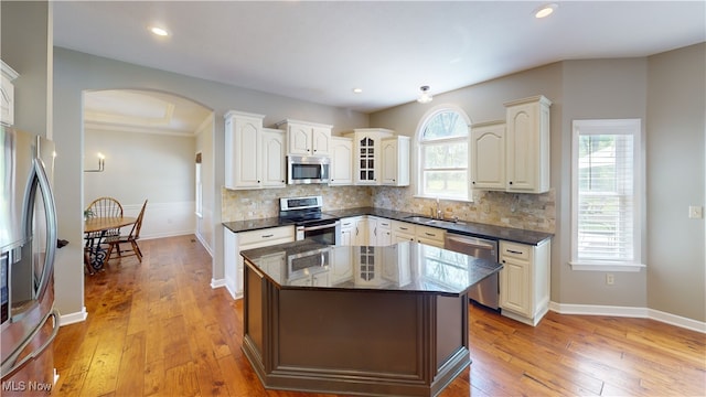 3130 Hollybrook Ln, Mogadore, OH 44260 - kitchen with appliances with stainless steel finishes, arched walkways, a sink, light wood finished floors, and backsplash