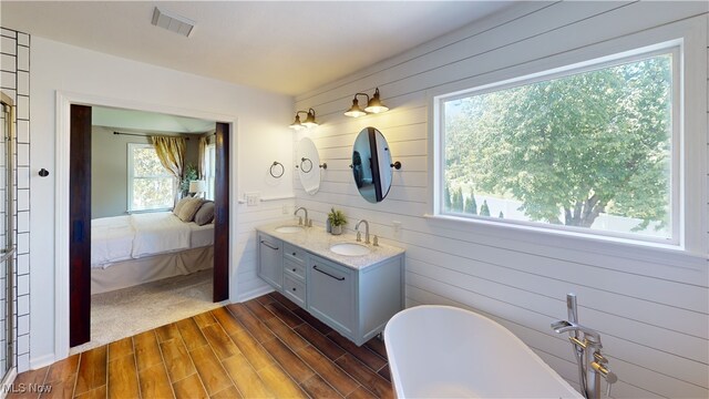 3130 Hollybrook Ln, Mogadore, OH 44260 - bathroom featuring double vanity, connected bathroom, a freestanding tub, wood finished floors, and wood walls