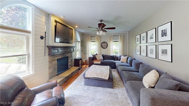 3130 Hollybrook Ln, Mogadore, OH 44260 - living area featuring wood finished floors, a ceiling fan, a stone fireplace, healthy amount of natural light, and wood walls