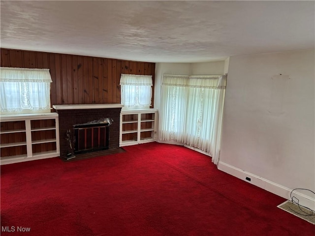 1733 E 47th St, Ashtabula, OH 44004 - unfurnished living room with a brick fireplace, baseboards, dark colored carpet, and wood walls