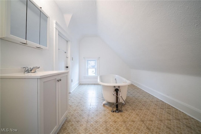 113 Lincoln Ct, Elyria, OH 44035 - bathroom with vaulted ceiling, vanity, a freestanding tub, baseboards, and a textured ceiling