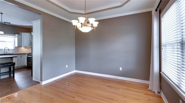 284 Kaylee Dr, Wadsworth, OH 44281 - unfurnished dining area with a sink, light wood finished floors, a chandelier, baseboards, and crown molding