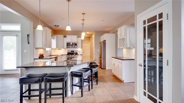 284 Kaylee Dr, Wadsworth, OH 44281 - kitchen with appliances with stainless steel finishes, a breakfast bar area, tasteful backsplash, a sink, and light tile patterned floors