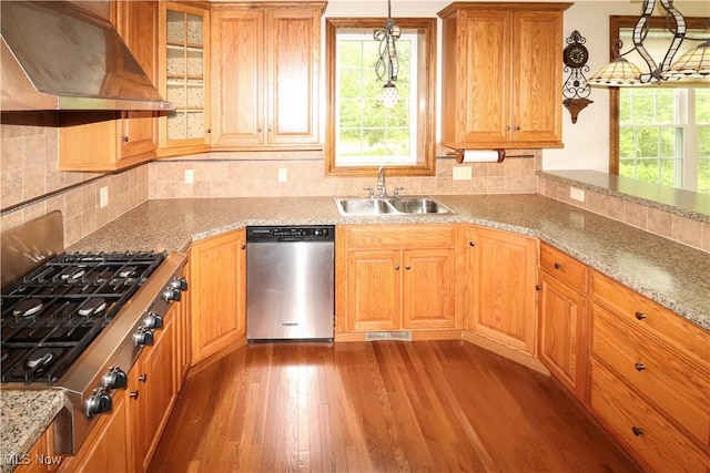 5280 Kapok Dr, Medina, OH 44256 - kitchen with appliances with stainless steel finishes, wall chimney range hood, a sink, hardwood / wood-style flooring, and decorative light fixtures