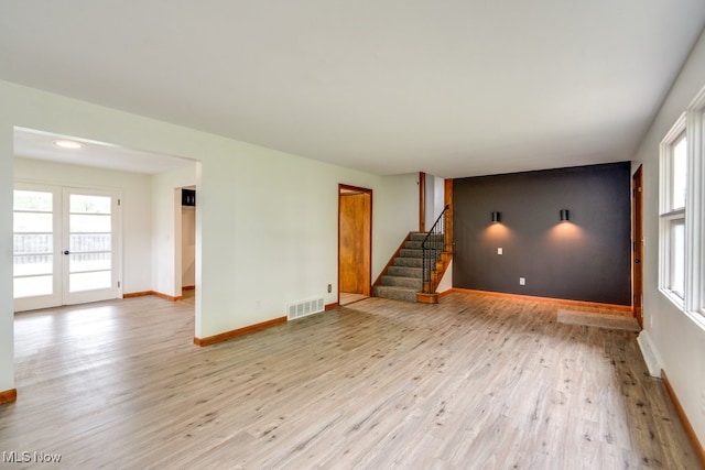 1924 Tiffany Dr NE, Warren, OH 44483 - unfurnished living room featuring light wood-style flooring, stairs, baseboards, and plenty of natural light