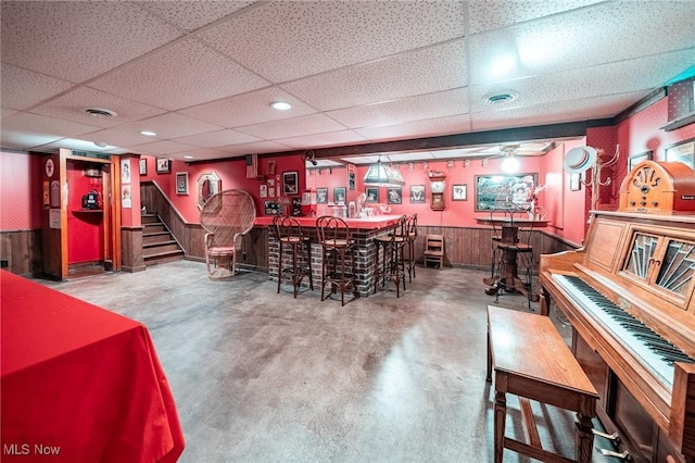 10576 Hemlock Ridge Dr, Chardon, OH 44024 - indoor bar with wainscoting, a drop ceiling, concrete flooring, stairway, and wood walls