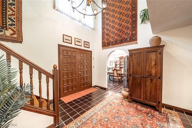 10576 Hemlock Ridge Dr, Chardon, OH 44024 - entrance foyer with arched walkways, a chandelier, dark tile patterned floors, baseboards, and a towering ceiling