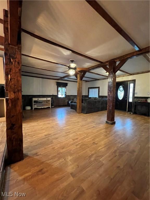 26938 County Rd 1, Coshocton, OH 43812 - unfurnished living room featuring wood finished floors, decorative columns, a wainscoted wall, ceiling fan, and beam ceiling