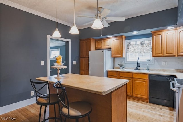 kitchen with freestanding refrigerator, black dishwasher, a sink, light countertops, and range