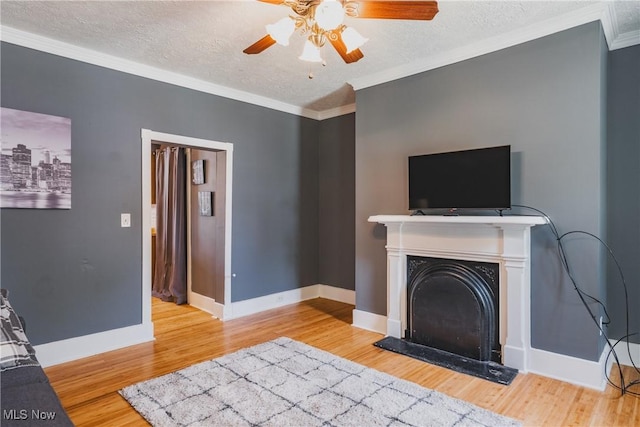 unfurnished living room with wood finished floors, ceiling fan, ornamental molding, baseboards, and a textured ceiling