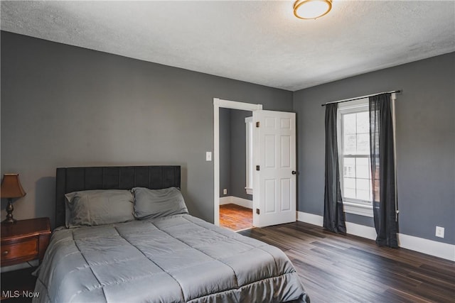 bedroom featuring wood finished floors, baseboards, and a textured ceiling