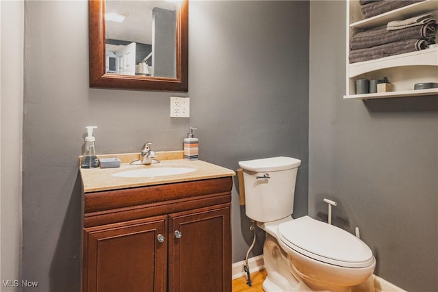 bathroom with vanity, toilet, and baseboards