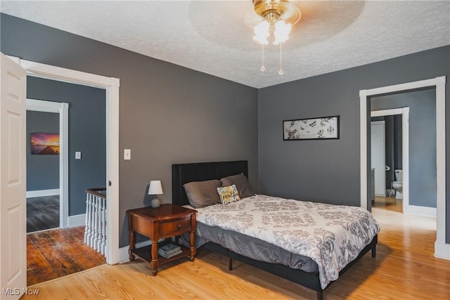 bedroom featuring wood finished floors, a textured ceiling, baseboards, and a ceiling fan