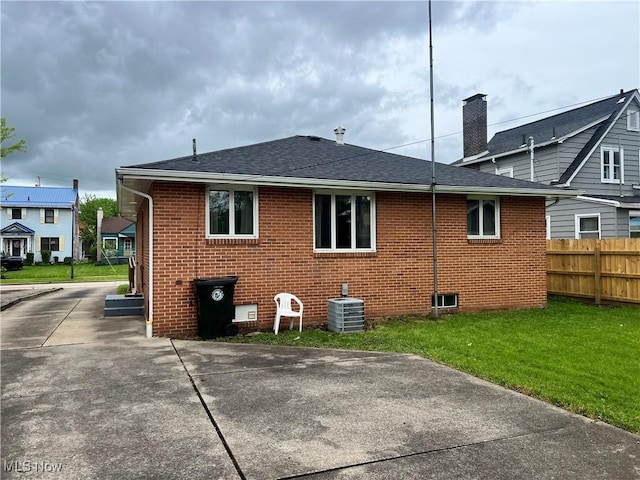 213 Kenmore Ave SE, Warren, OH 44483 - rear view of property with a shingled roof, brick siding, central AC, and a chimney