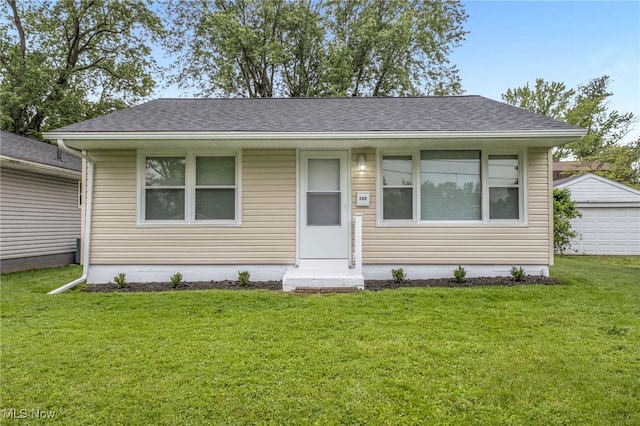180 Glenn St, Barberton, OH 44203 - bungalow featuring a front yard, a shingled roof, a garage, and an outdoor structure