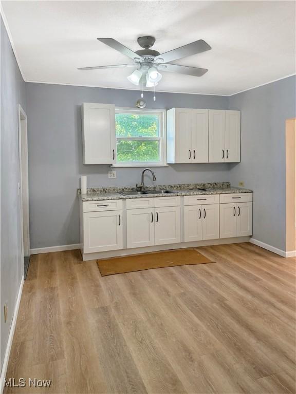 5417 Brow Ave, Newburgh Heights, OH 44105 - kitchen featuring a sink, a ceiling fan, white cabinetry, light stone countertops, and light wood-style flooring