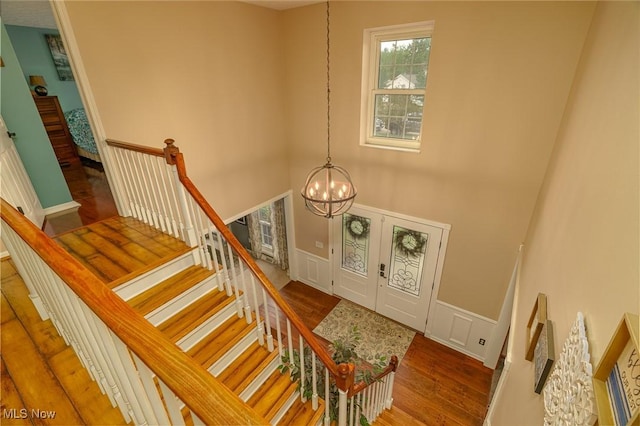 20686 Wildwood Ln, Strongsville, OH 44149 - stairs featuring a chandelier, wood finished floors, wainscoting, a high ceiling, and a decorative wall