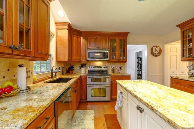 20686 Wildwood Ln, Strongsville, OH 44149 - kitchen featuring appliances with stainless steel finishes, a sink, glass insert cabinets, light stone countertops, and decorative backsplash