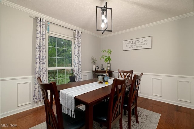 20686 Wildwood Ln, Strongsville, OH 44149 - dining room with wood finished floors, crown molding, wainscoting, a textured ceiling, and a decorative wall