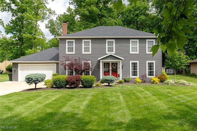 20686 Wildwood Ln, Strongsville, OH 44149 - colonial-style house featuring a chimney, a front yard, driveway, a garage, and roof with shingles