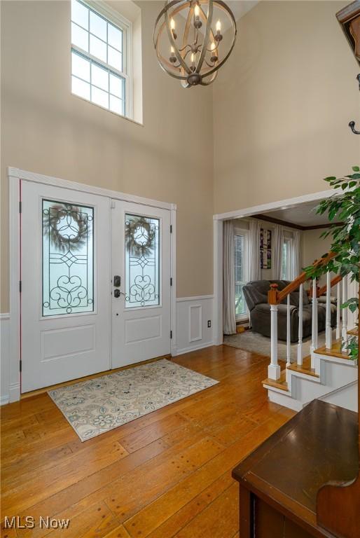 20686 Wildwood Ln, Strongsville, OH 44149 - foyer entrance featuring a chandelier, hardwood / wood-style flooring, a high ceiling, wainscoting, and stairs