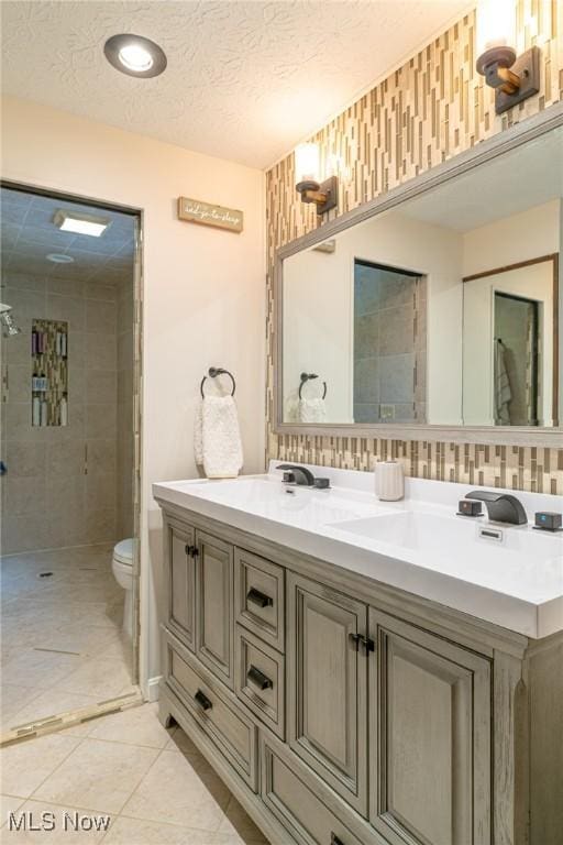 20686 Wildwood Ln, Strongsville, OH 44149 - full bathroom featuring double vanity, toilet, a tile shower, a textured ceiling, and tile patterned floors