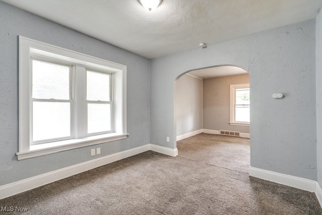 1866 17th St SW, Akron, OH 44314 - empty room with arched walkways, carpet flooring, and baseboards