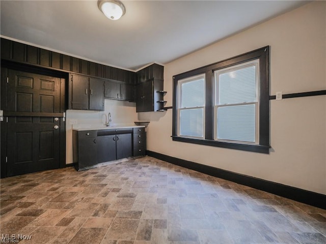 2179 W 106th St, Cleveland, OH 44102 - kitchen featuring baseboards, light stone finish flooring, a sink, and open shelves