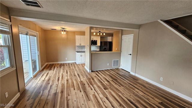 3970 Royal Liverpool Dr Unit A, Uniontown, OH 44685 - unfurnished living room featuring wood finished floors, a textured ceiling, baseboards, and stairway