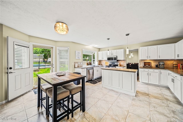 20393 Wildwood Ln, Strongsville, OH 44149 - kitchen featuring stainless steel appliances, healthy amount of natural light, white cabinetry, backsplash, and a textured ceiling