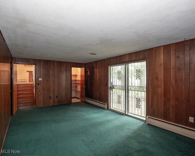 433 University Ave, Elyria, OH 44035 - carpeted empty room featuring a baseboard radiator, wooden walls, and stairs