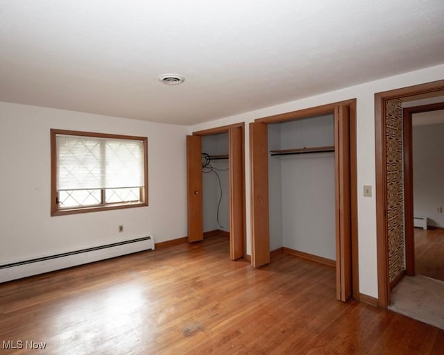 433 University Ave, Elyria, OH 44035 - unfurnished bedroom featuring multiple closets, a baseboard heating unit, light wood-type flooring, baseboards, and a baseboard radiator